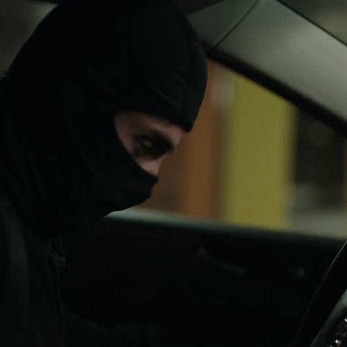 A thief in a balaclava behind the steering wheel